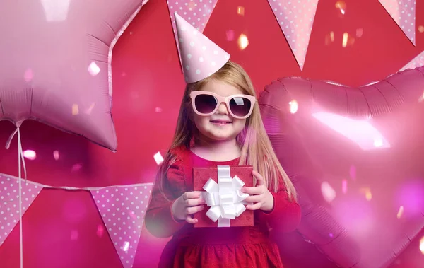 Adorabile bella ragazza con palloncini rosa e rosso regalo e cappello di compleanno — Foto Stock