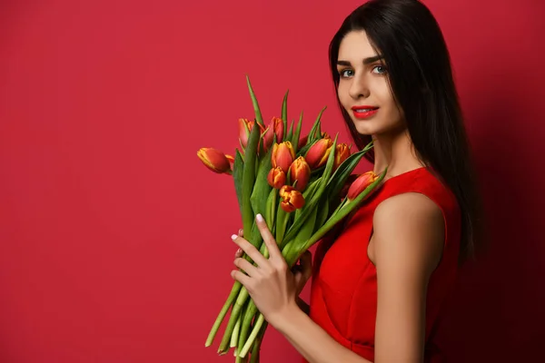 Hermosa mujer con ramo de flores de tulipán en vestido rojo y mirando a la esquina con espacio de copia de texto vacío — Foto de Stock