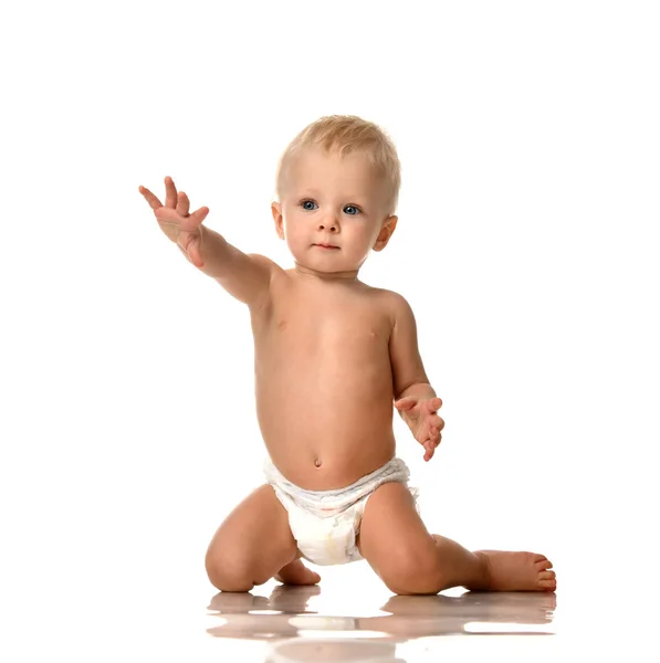 Маленький мальчик сидит голый в подгузнике с поднятой рукой — стоковое фото