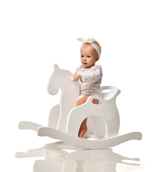 Toddler baby girl is riding swinging on a rocking chair toy horse over white — Stock Photo, Image