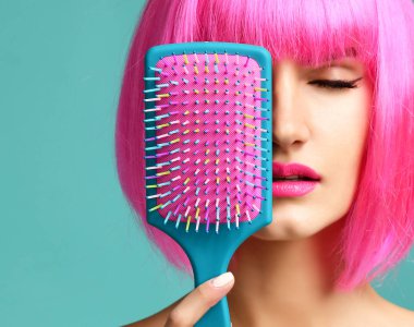 Esmer kadın mutlu moda portre portre renkli pembe mavi sarı küçük saç tarak fırça pembe peruk ağzıyla kapatın