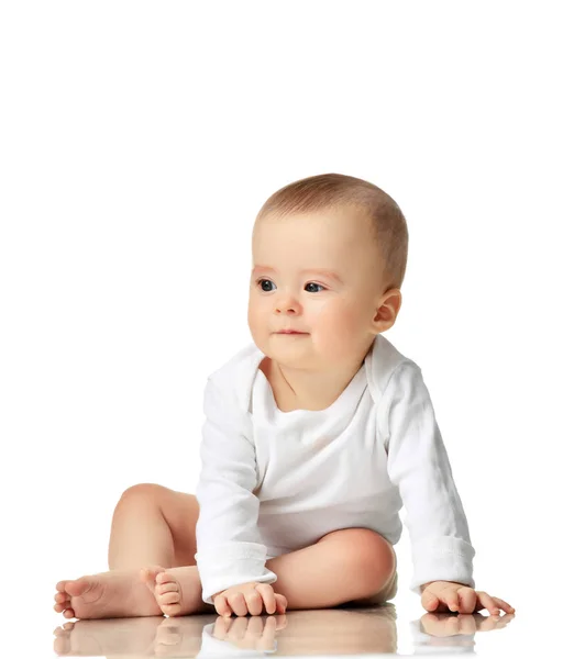7 месяцев младенец ребенок девочка малышка сидит в белой рубашке, глядя на угол — стоковое фото