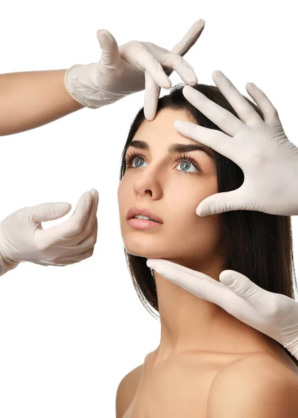 Läkare händerna i medicinska handskar tryck vacker ung kvinna ansikte med slutna ögon efter plastikkirurgi — Stockfoto