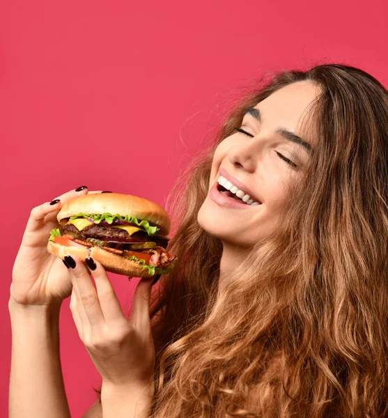 Nő tartsa barbecue hamburger szendvics éhes száj, rózsaszín, piros háttér — Stock Fotó