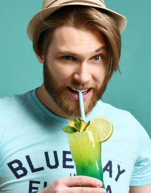 Margarita kokteyl içki suyu kameraya bakarak mutlu içme şapkalı genç adam 