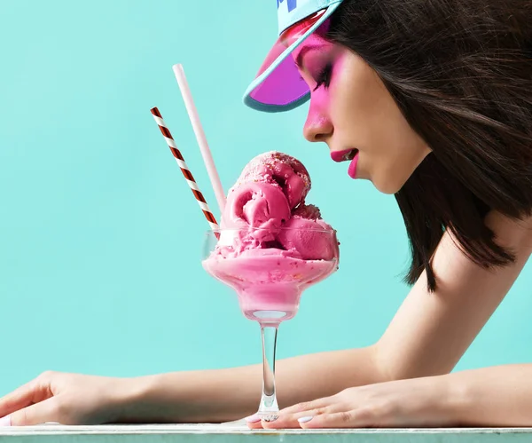 Jonge vrouw in roze hoed aardbei dessert van ijs eten op moderne licht blauw — Stockfoto