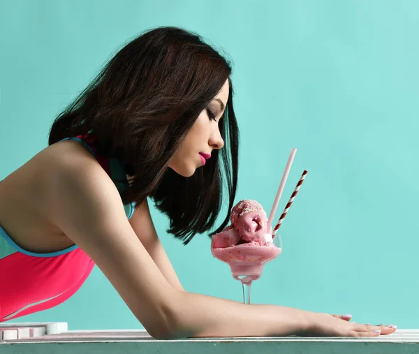 Ung kvinna i rosa hatt äta jordgubbs glass dessert på moderna ljusblå — Stockfoto