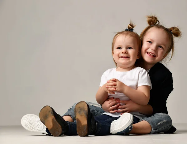 Birlikte mutlu gri gülümseyen sarılma oturan güzel küçük kız kızlar çocuklar — Stok fotoğraf