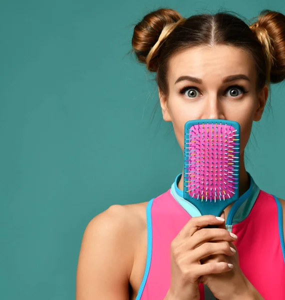 Jovem mulher surpreso fechar a boca com rosa e azul escova de pente de cabelo grande — Fotografia de Stock