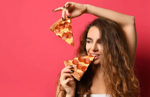 Молодая красивая женщина есть кусок пиццы пепперони улыбаясь на темно-красный — стоковое фото