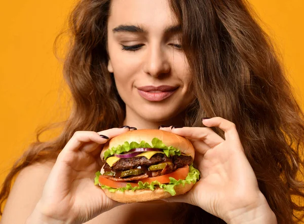 Vrouw eet Hamburger sandwich met hongerige mond op gele achtergrond — Stockfoto