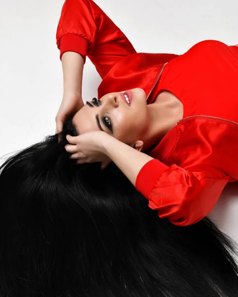 Jovem bela mulher morena deitada no chão em vermelho jaqueta pano vista superior com cabelos longos olhando para cima — Fotografia de Stock