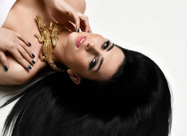 躺在地板上的年轻漂亮的黑发妇女穿着昂贵的金鳄鱼首饰与长发 — 图库照片