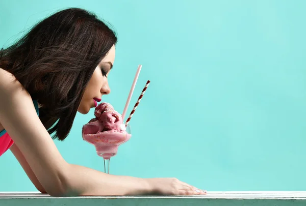Pembe şapkalı genç kadın yemek çilekli dondurma tatlı üzerinde modern açık mavi — Stok fotoğraf
