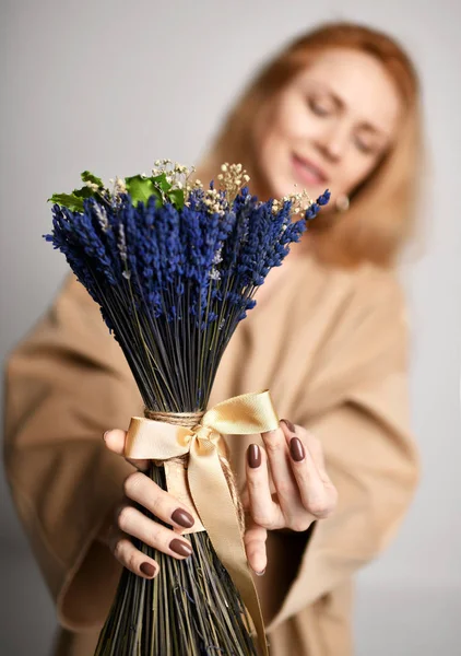 Hermosa mujer de pelo rojo usando marrón amarillo diseñadores vestido abrigo y ramo de flores azules lavanda —  Fotos de Stock