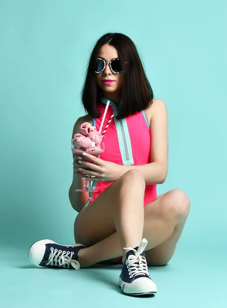 Young woman in pink hat eat strawberry ice-cream dessert on modern light blue — Stock Photo, Image