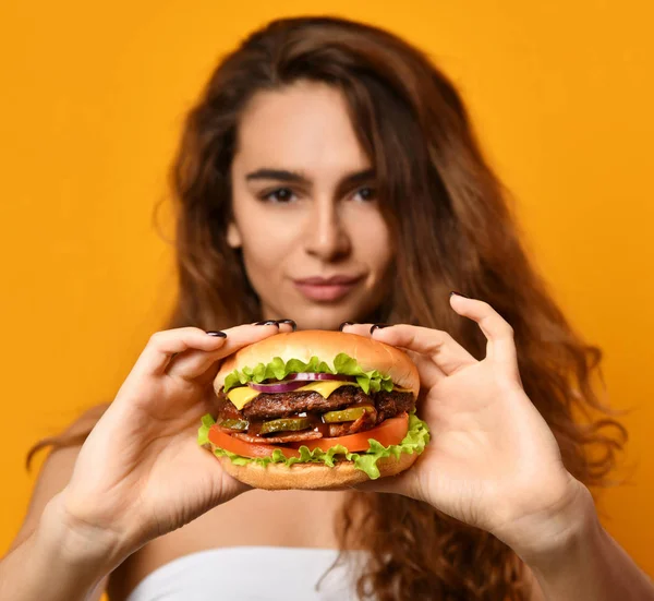 Жінка їсть бургер сендвіч з голодним ротом на жовтому фоні — стокове фото