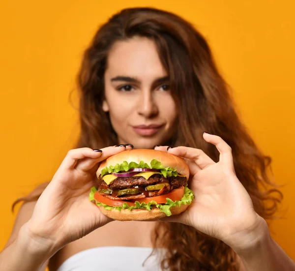 Woman eat burger sandwich with hungry mouth on yellow background — Stock Photo, Image