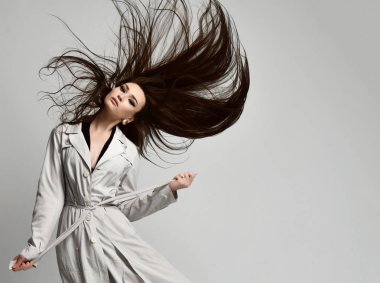 Güzel esmer hipster kadın rüzgarlı saç poz ile gri sonbahar ceketli