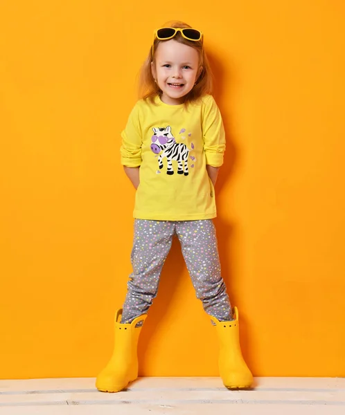 Güneş gözlüğü ve sarı tişört poz genç çocuk bebek kız çocukta sarı lastik çizmeler — Stok fotoğraf