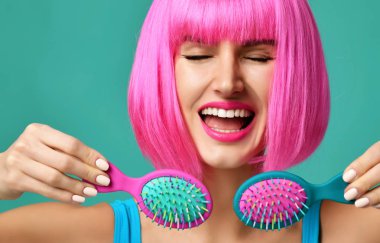 Esmer kadın mutlu moda portre portre tutun iki küçük pembe mavi küçük saç tarak fırça içinde pembe peruk