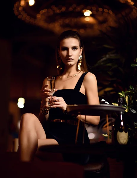 Beautiful sexy fashion brunette woman in expensive interior restaurant drinking champagne waiting on dark cafe — Stock Photo, Image