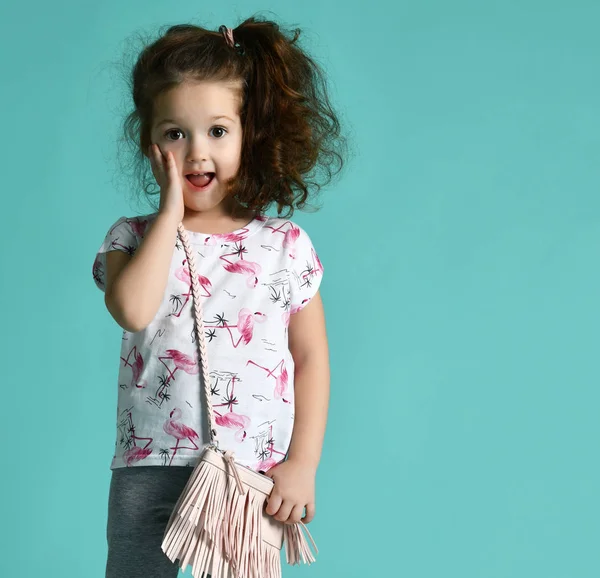 Cute curly baby girl kid in white t-shirt and blue jeans smiling on blue mint — Stock Photo, Image