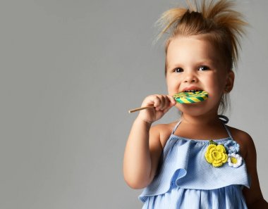 Yürümeye başlayan çocuk kız çocuk büyük tatlı lolipop şeker Grey mavi elbiseli genç güzel