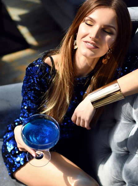 Wanita berambut cokelat fashion duduk di restoran interior mahal minum minuman keras margarita biru melihat sudut — Stok Foto