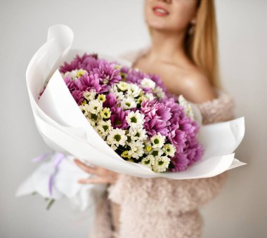 Güzel kadın tutun kasımpatı çiçekleri beyaz ve mor mutlu gülümseyerek, buket