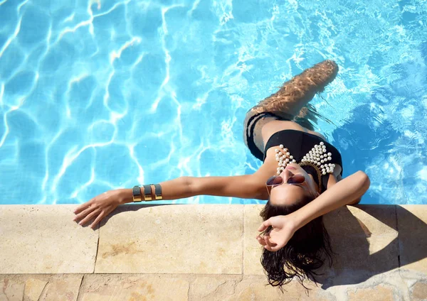 Vrouw ontspannen in blauw luxe zwembad recreatie op witte natuursteen — Stockfoto