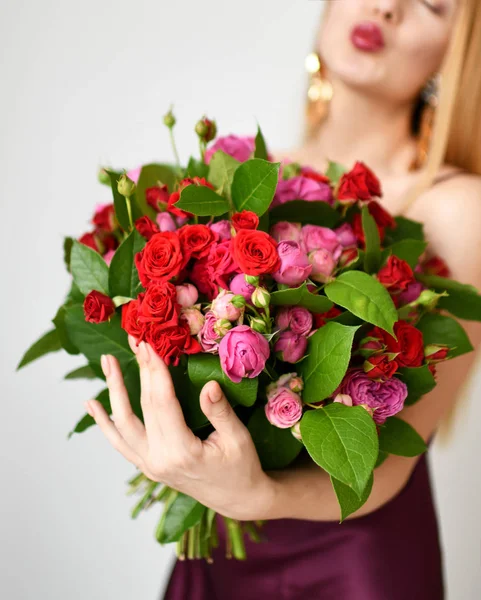 美しい女性が幸せな笑顔灰色の赤とピンクのバラの花の花束を保持します。 — ストック写真