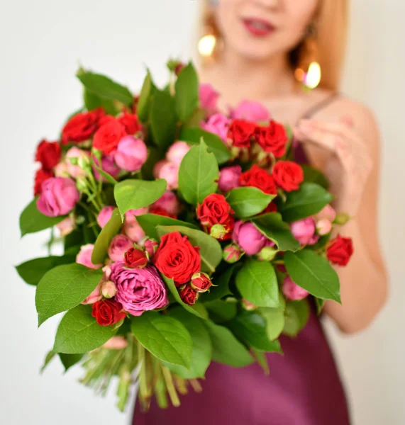 Szép nő, tartsa a virágok piros-rózsaszín rózsa csokor boldog, mosolyog a szürke — Stock Fotó