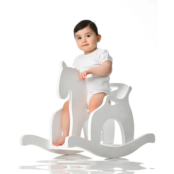 Toddler baby girl is riding swinging on a rocking chair toy horse over white — Stock Photo, Image