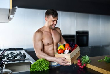  güçlü kas spor adam mutfak kutu elinde taze yiyecek sebze dolu üzerinde ayakta gülümseyen arıyorsunuz 