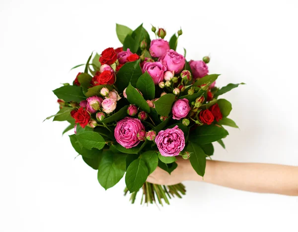 Beautiful woman hand hold bouquet of red and pink roses peony flowers on white — Stock Photo, Image