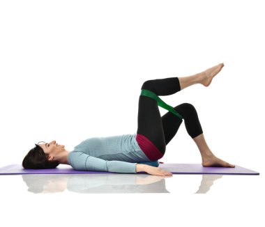 Kadın doğum sonrası egzersiz yaparken egzersiz. Beyaz izole kauçuk direniş band ile çalışma dışarı kadın fitness eğitmeni