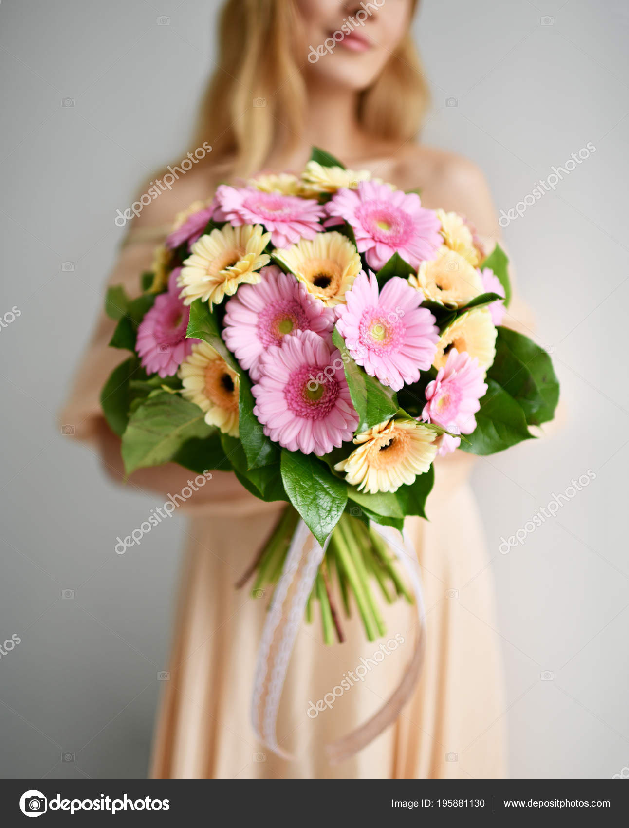 美丽的妇女举行非洲菊花束粉红色和黄色快乐微笑灰色 图库照片 C Dml5050 美丽的妇女举行非洲菊花束粉红色和黄色快乐微笑灰色 图库照片 C Dml5050