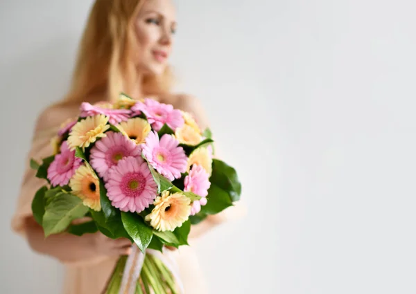 Gyönyörű nő hold csokor gerbera virágok rózsaszín és sárga boldog, mosolyog a szürke — Stock Fotó