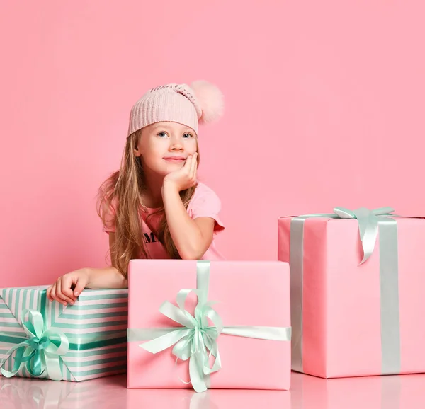 선물 상자 뒤에 앉아 있는 여자 아이는 선물 상자 안에뭐 가 들었는지 추측하며 선물을 준비하고 핑크 색을 기다리고 있습니다. — 스톡 사진