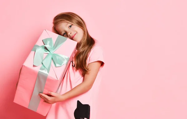 Χριστούγεννα και Πρωτοχρονιά. Ξανθιά κοπέλα με ροζ φόρεμα κρατώντας ένα μεγάλο κουτί δώρων, αγκαλιάζει, έχει το καλύτερο σε ροζ — Φωτογραφία Αρχείου
