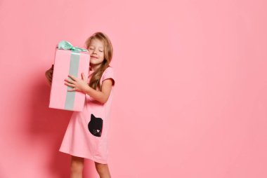 Noel ve Yeni Yıl. Pembe elbiseli sarışın kız uzun zamandır beklenen büyük bir hediye kutusu taşıyor ve pembeye sarılıyor. Pankart