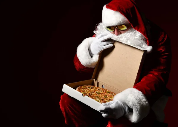 Noel Baba pizza kutusunu kapağında fotokopi aletiyle açıyor ve içine bakıyor, arzuluyor. Yeni yıl ve Xmas fast food — Stok fotoğraf