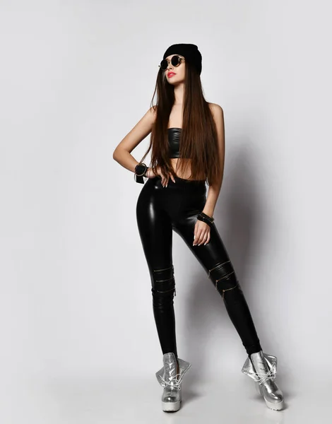 Brutal flicka i runda solglasögon, svart hatt, tight läder leggings med blixtlås är cool poserar tittar upp st kopiera utrymme — Stockfoto