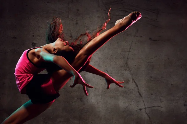 Danseuse de rue danseuse sautant vers le haut dansant dans la lumière néon faisant des exercices de gymnastique — Photo