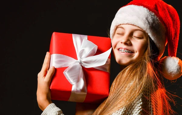 Feliz sonrisa con los ojos cerrados adolescente con frenos abrazando la caja roja de regalo de Navidad largamente esperada con cinta — Foto de Stock