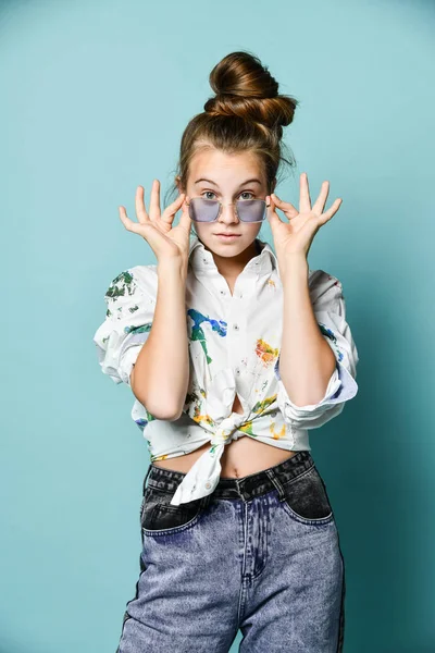 Verrast tiener meisje jonge vrouw in wit shirt met verf vlekken kijken naar ons over bril aanpassen, vasthouden — Stockfoto