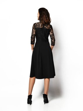 Genç ve güzel bir kadın yeni moda poz veriyor. Uzun, siyah bir kış elbisesi. Mutlu bir gülümseme.