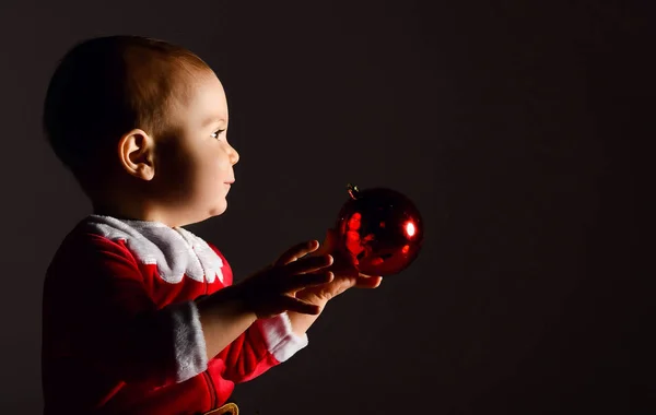 Petit enfant garçon tout-petit en santa claus nouvelle année costume heureux souriant tenant arbre de Noël boule de verre rouge — Photo