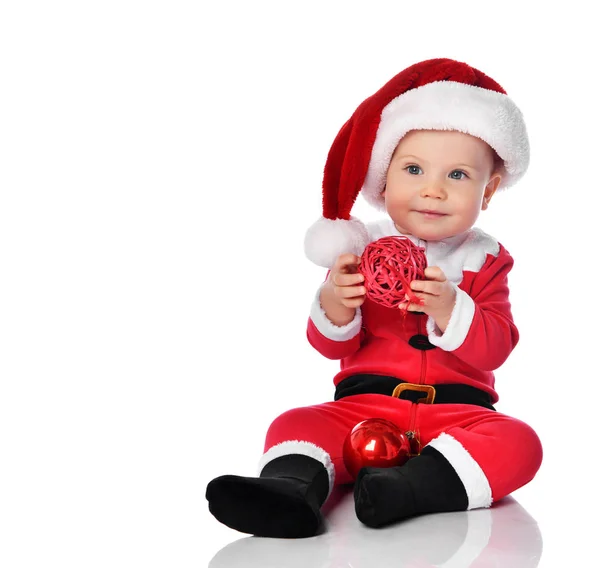 Μικρό παιδί αγόρι νήπιο στο κοστούμι Άγιος Βασίλης και καπέλο χαρούμενος χαμογελώντας με κόκκινο δώρο μπάλα ελάτη διακόσμηση έτοιμο να γιορτάσει — Φωτογραφία Αρχείου